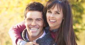 Caucasian couple woman man late 30s early 40s smiling into camera autumn