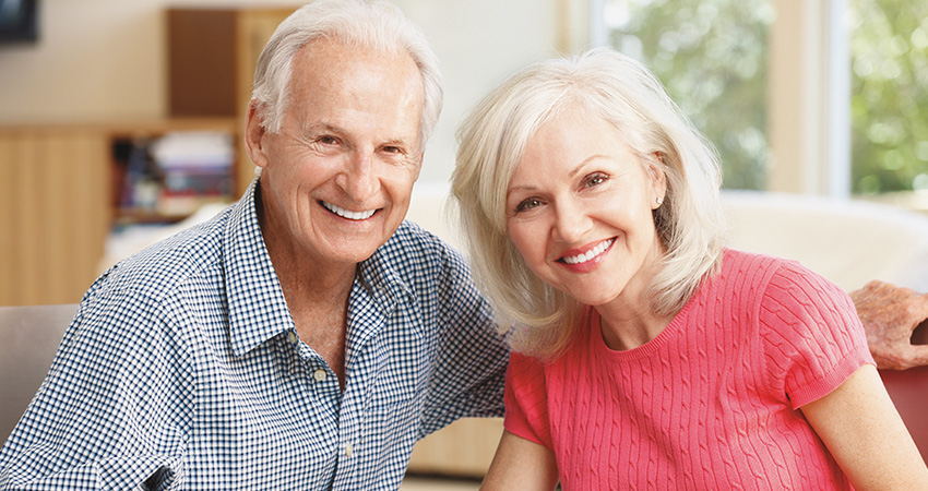 Retired couple relaxes in home and smiles to reveal dental implants