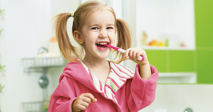 Young girl brushes her teeth in washroom