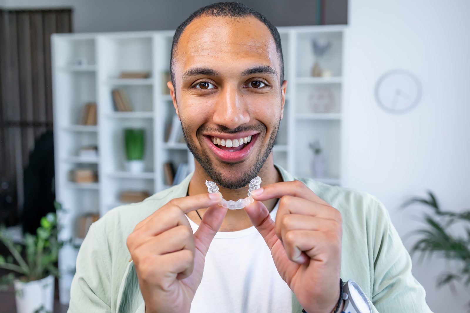 A clear aligner held up in a hand
